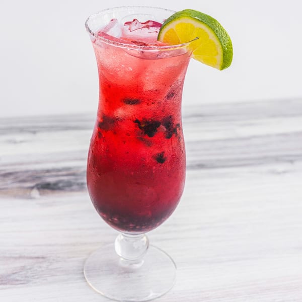 A vibrant red Prados Modern Mexican Cantina cocktail with ice and lime garnish.
