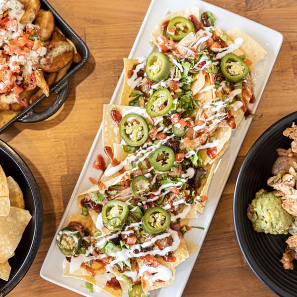 Prados Modern Mexican Cantina's loaded nachos with jalapeños, pico de gallo, and crema, alongside other dishes.