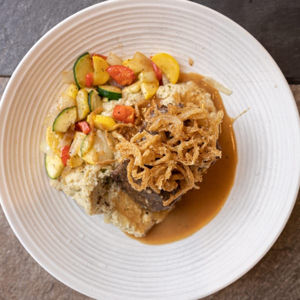 Braised short rib with mashed potatoes, fried onions, and roasted zucchini, squash, and peppers.