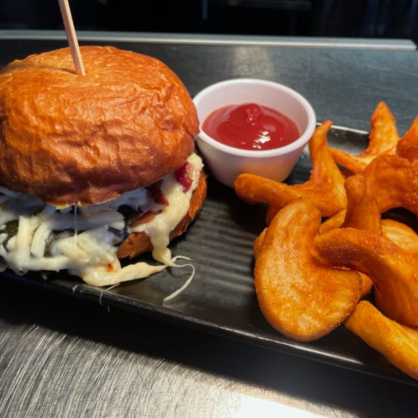 A burger with melted cheese and bacon, served with a side of wedge fries and ketchup.