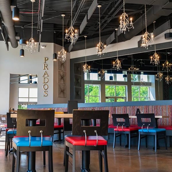Interior of Prados Modern Mexican Cantina with colorful chairs, chandeliers, and large windows.