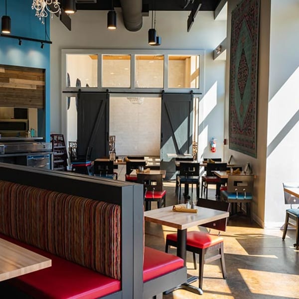 Bright, modern Prados Modern Mexican Cantina dining room with booths, tables, and a large decorative tapestry.