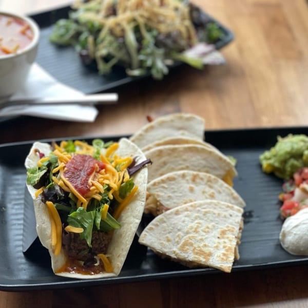 A Prados Modern Mexican Cantina plate with a taco, quesadillas, guacamole, pico de gallo, and sour cream.