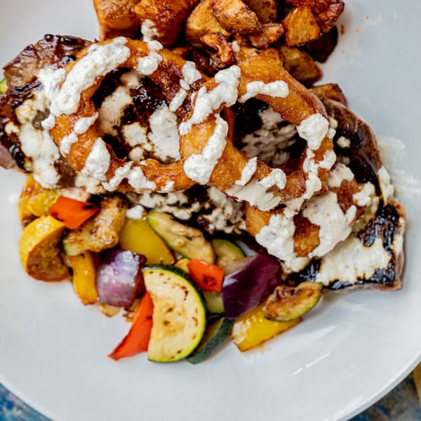 Prados Modern Mexican Cantina's steak with onion rings, crema, roasted potatoes, and mixed vegetables.