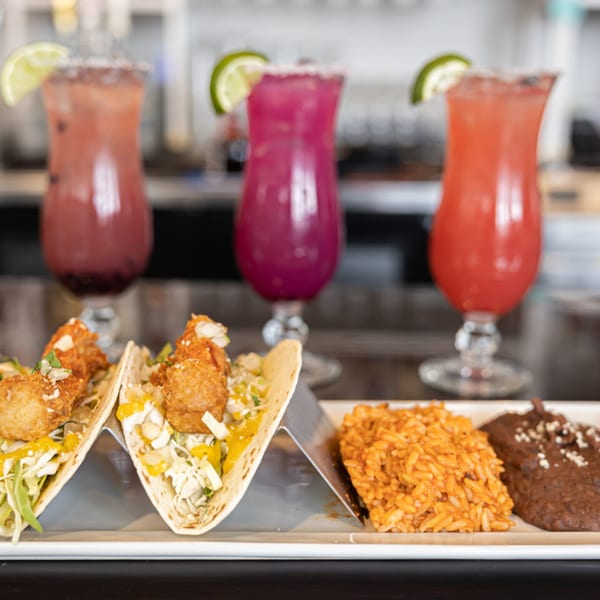 Prados Modern Mexican Cantina's fried shrimp tacos with rice, beans, and three colorful margaritas.