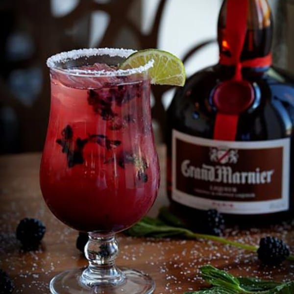 A Prados Modern Mexican Cantina blackberry margarita with a lime wedge and salted rim.