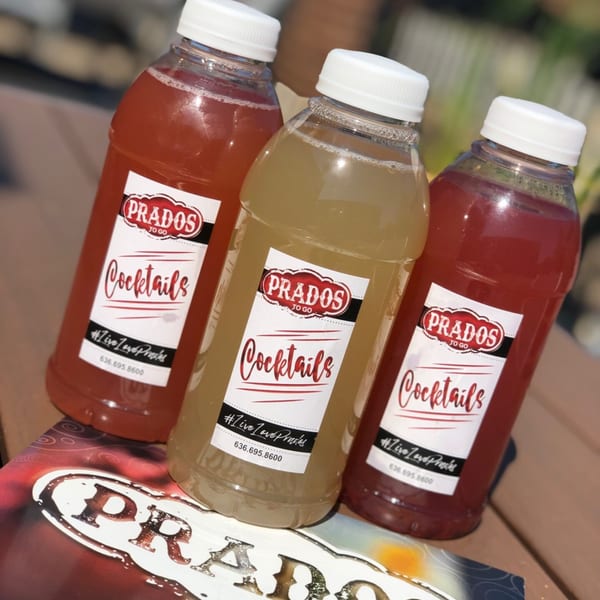 Three Prados Modern Mexican Cantina to-go cocktail bottles, two red and one yellow, on a menu.