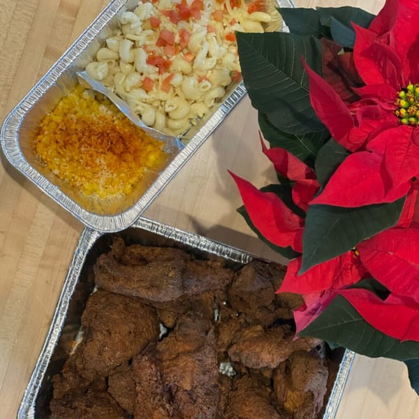 Mexican catering spread with mac and cheese, corn, and fried chicken next to a red poinsettia.
